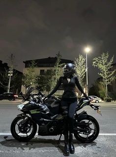 a woman sitting on top of a motorcycle in the middle of a parking lot at night