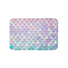 a bath mat with mermaid scales in pastel blue, pink and purple colors on it