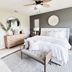 a white bed sitting in a bedroom next to a dresser and mirror on top of a wall