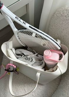 a tennis racket is in a white bag on the floor next to some shoes