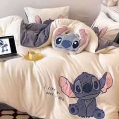 a laptop computer sitting on top of a bed next to pillows and blankets with cartoon characters