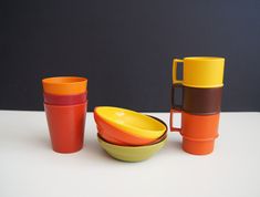 three different colored bowls and cups sitting on a table