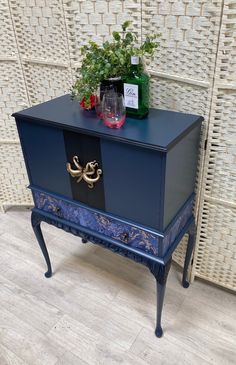 a blue cabinet with flowers on top and a bottle of wine sitting on it's side