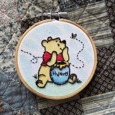 a winnie the pooh cross stitched on to a piece of fabric with a butterfly flying over it