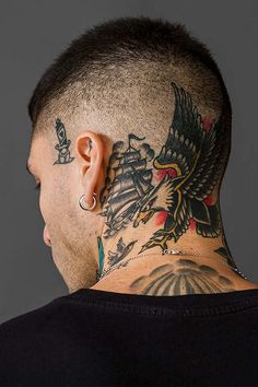 the back of a man's head with tattoos on his neck and ear piercings