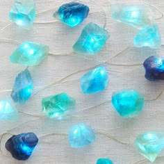 blue and green glass beads are on a white table cloth, with string attached to them