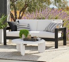 a white couch sitting on top of a wooden table next to a purple flower field