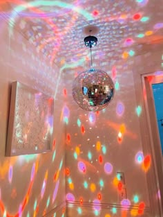 a disco ball hanging from the ceiling in a room with colorful lights on it's walls