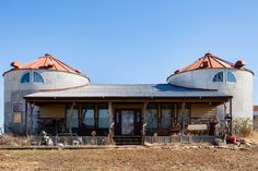 two round metal buildings sitting on top of a dry grass field