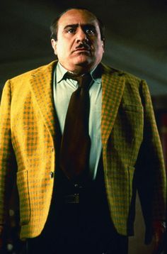 a man in a yellow jacket and tie is looking at the camera with an intense look on his face