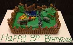 a birthday cake made to look like a zoo scene with animals and bamboo sticks on it