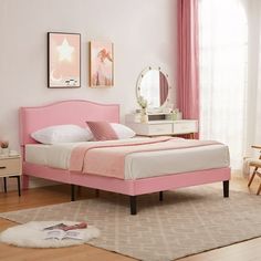 a bedroom with pink bedding, dresser and mirror in the corner next to a window