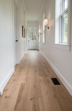 an empty hallway with wood floors and white walls