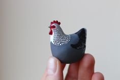 a hand holding a small toy chicken in it's palm