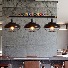 three lights hanging from the ceiling above a table with chairs and pool balls on it