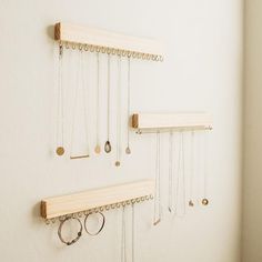 several necklaces are hanging on the wall with wooden pegs attached to hooks and chains