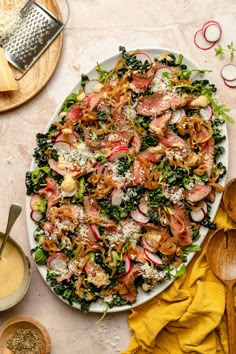 a salad with meat, radishes and parmesan cheese on a white plate