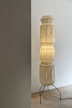 a tall lamp sitting on top of a metal stand next to a white wall and floor