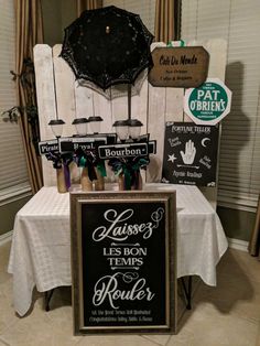 a table topped with a sign and an umbrella next to a wall mounted chalkboard