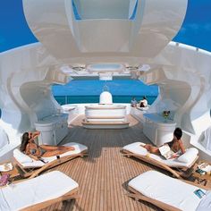 two women lounging on chaise lounges in the back of a motor yacht