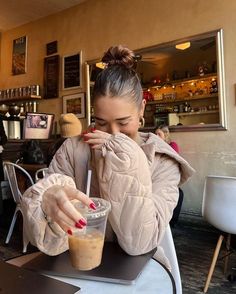 a woman sitting at a table with a drink in her hand