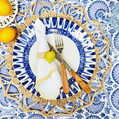 a blue and white plate topped with two lemons next to a knife and fork