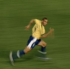 a soccer player running with the ball in his hand and blurry image behind him