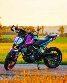 a pink and blue motorcycle parked on the side of a road