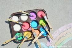 paintbrushes and paints in a tray on the ground