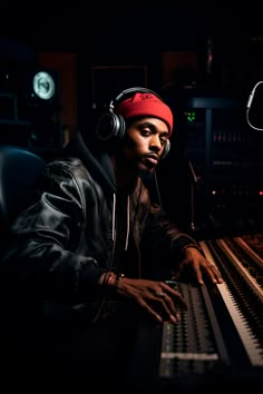 a man wearing headphones sitting in front of a mixing desk with an electronic keyboard