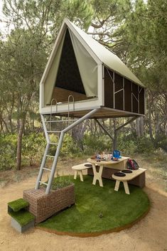 a tent is set up in the middle of a grassy area with picnic tables and benches underneath it