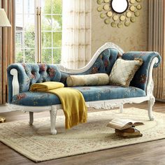 a blue and white couch sitting in front of a window next to a rug on top of a wooden floor