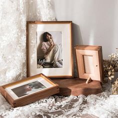 three wooden frames sitting next to each other on a white lace covered tablecloth with flowers