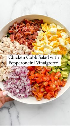 chicken cobb salad with pepperonii vinaigrete in a white bowl on a marble countertop