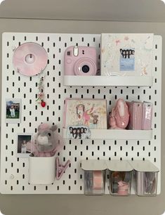 a white pegboard with shelves holding various items and pictures on it's sides