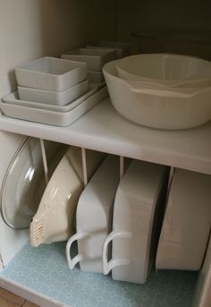 there are many dishes and bowls on the shelf