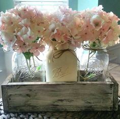 some pink flowers are in mason jars on a table