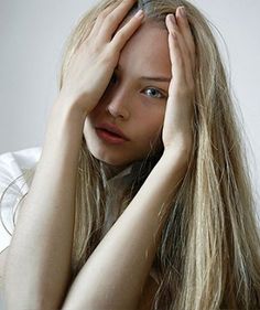 a woman with long blonde hair holding her head