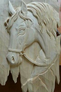 a wooden carving of a horse's head with bridled manes on it