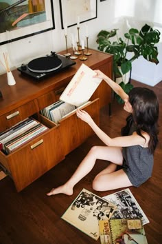 a woman sitting on the floor holding up a record player