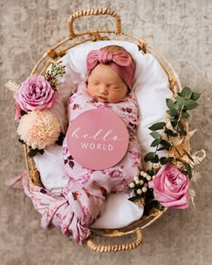 a newborn baby is sleeping in a wicker basket with flowers and a sign that says i'm here