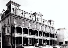 an old black and white photo of a building with cars parked in front of it