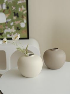 two white vases sitting on top of a table next to each other with flowers in them