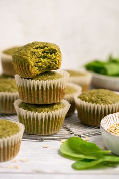 several cupcakes stacked on top of each other next to some green leaves and bowls