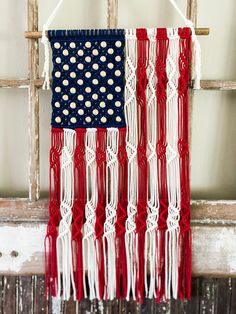 an american flag made out of rope hanging on a window sill with red, white and blue colors