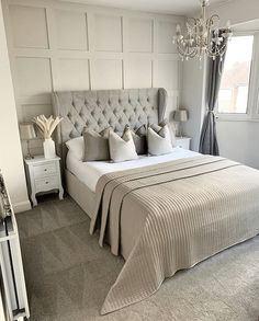 a bedroom with a large bed, chandelier and two nightstands in it