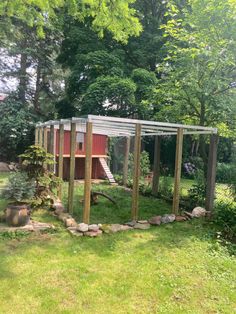 a chicken coop in the middle of a grassy area with rocks and trees around it