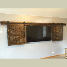 a flat screen tv mounted to the side of a wall next to wooden shutters