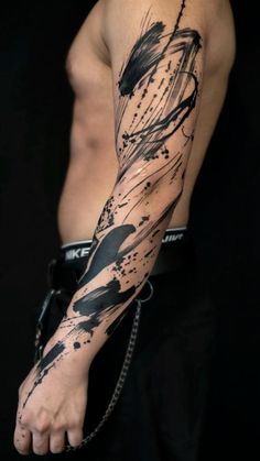 a man's arm with black ink splattered on it and chains around his ankles