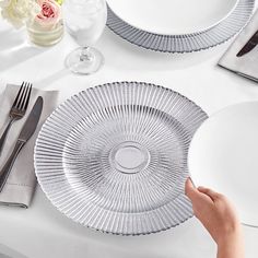 a person is setting a table with plates and silverware